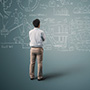 man standing looking at blackboard